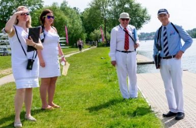 Two women in white and two men in summer suits and ties looking out onto the regatta