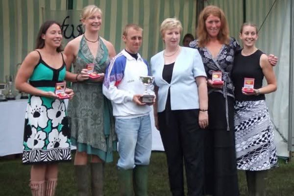 4 women and male cox being presented with medals atnd trophy