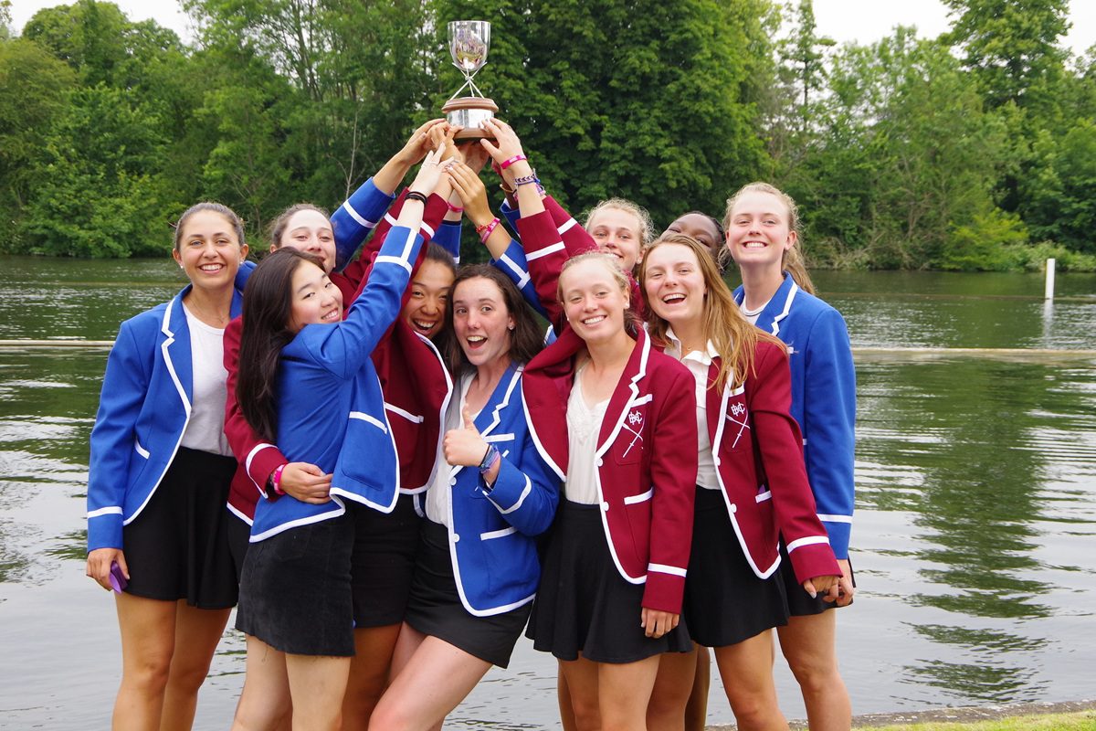 8 junior rowers in blazers holding up trophy