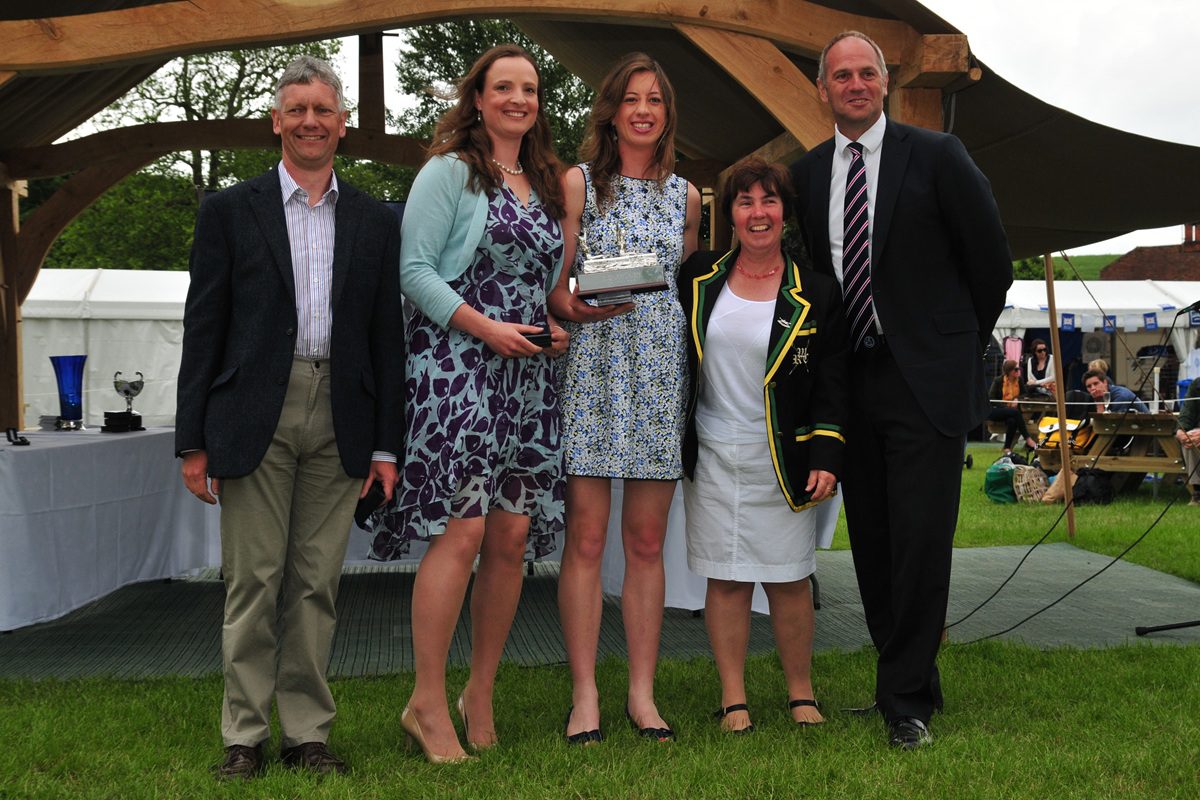 2 athletes with trophy and 3 other people
