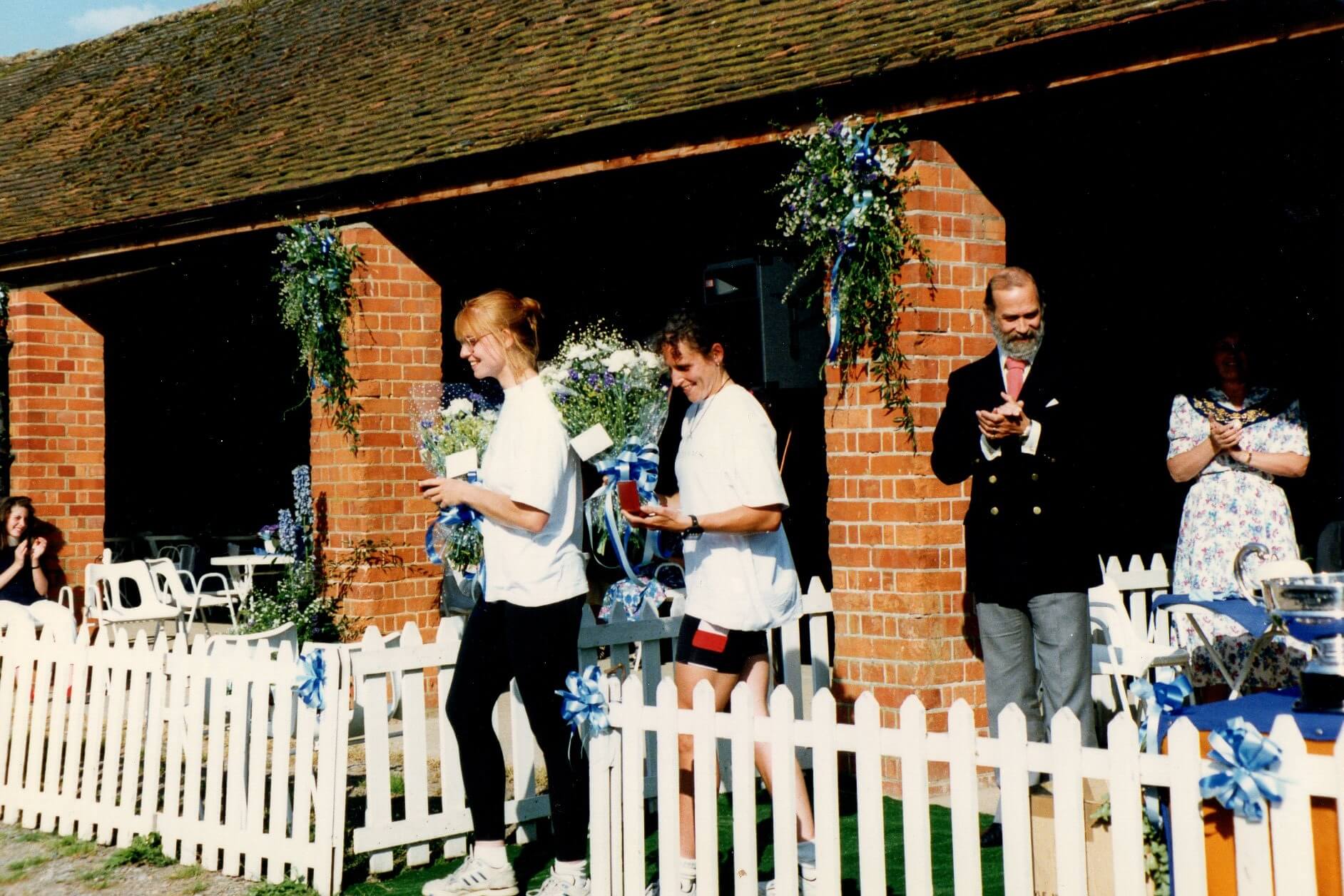 2 women receiving medals and bouquets