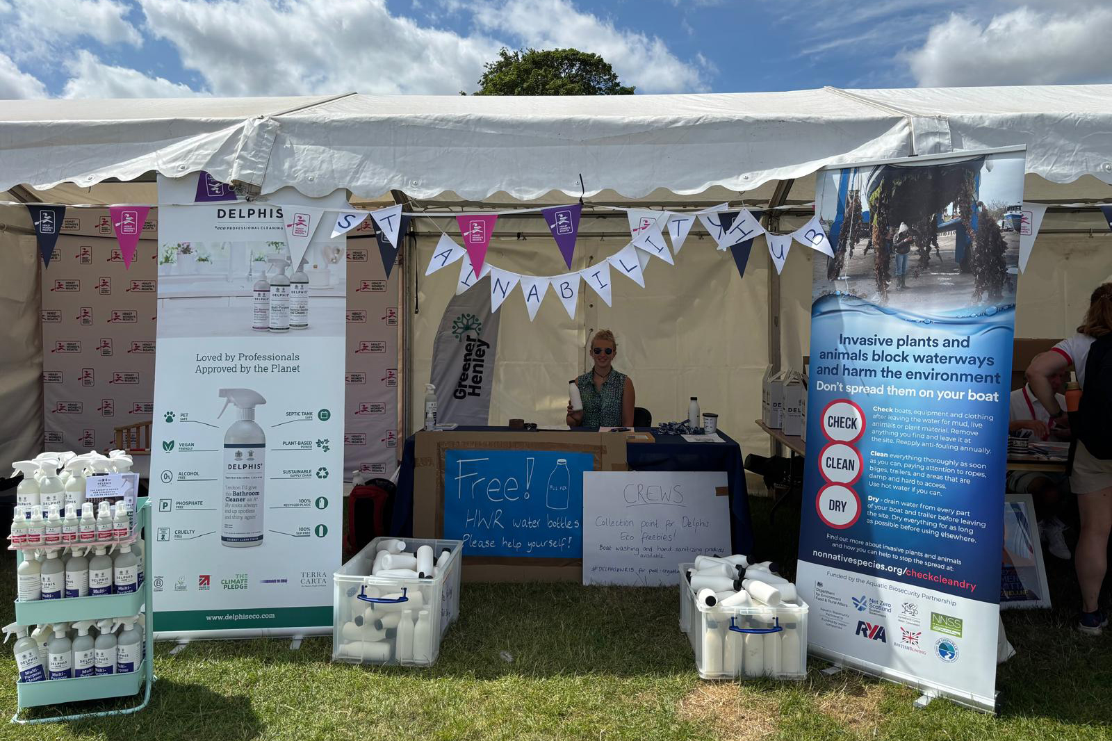 A woman is pictured in a tent surrounded by banners and signs promoting sustainability
