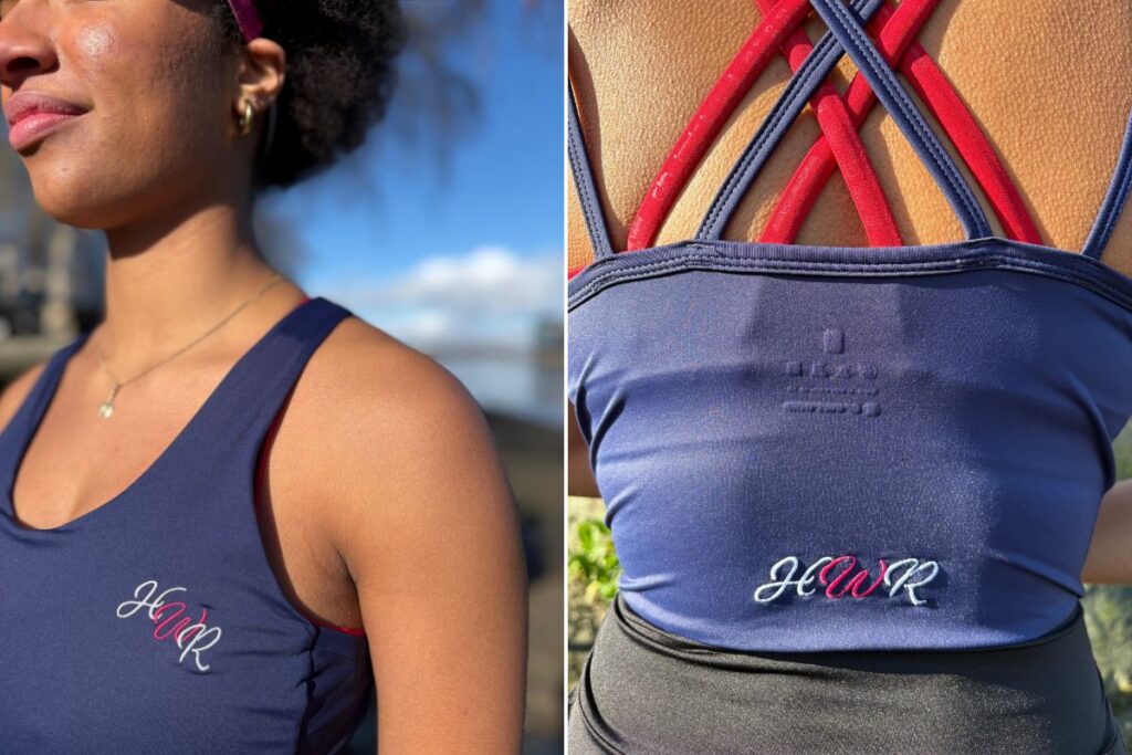 A rower is pictured from the side and behind wearing a strappy navy top embroidered with 'HWR' in white and pink italic lettering. The straps are pink and navy.