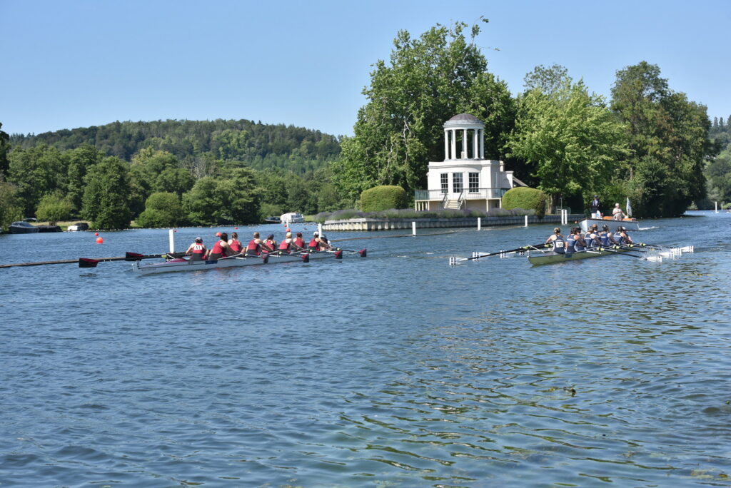Two eights are pictured racing against a background of a temple on an island