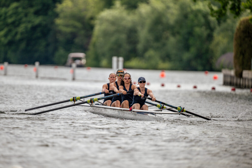 A coxed four is pictured racing away from the camera wearing dark blue